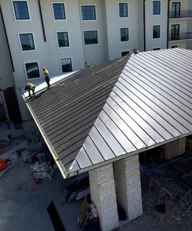 Crew installing standing seam metal roof panels on a commercial project in Brookings